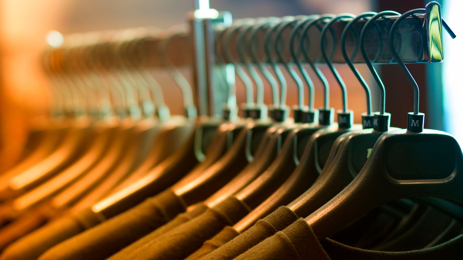 A row of neatly arranged clothes hanging on wooden hangers on a rack
