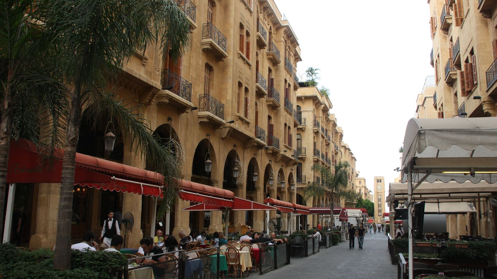A lively cafe-lined avenue in Beirut with classic buildings and outdoor seating