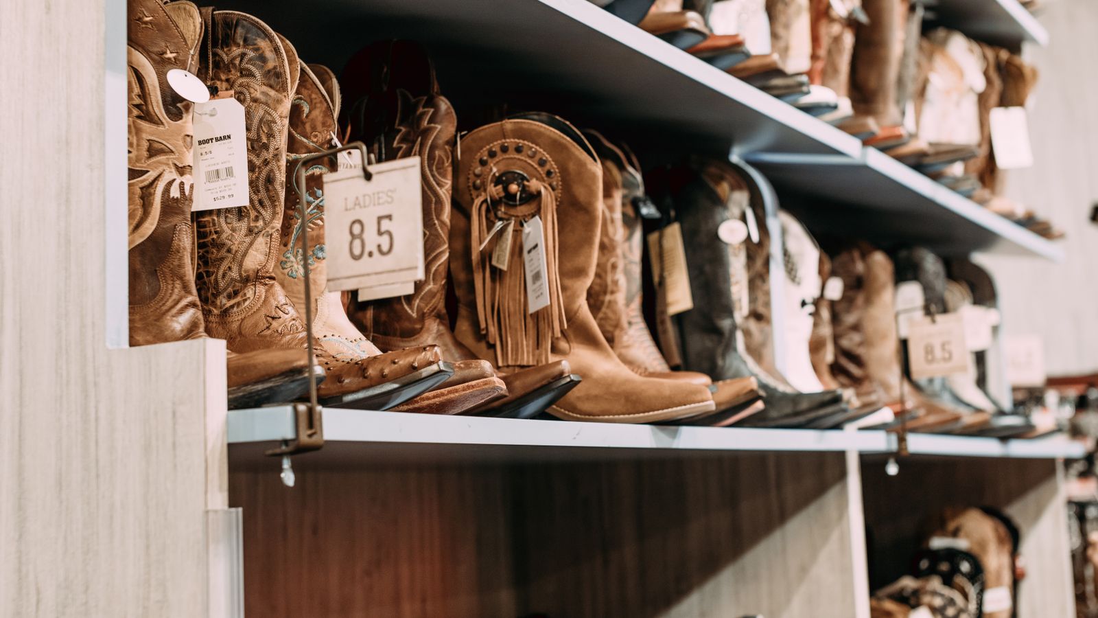 A variety of cowboy boots displayed on shelves in a footwear store