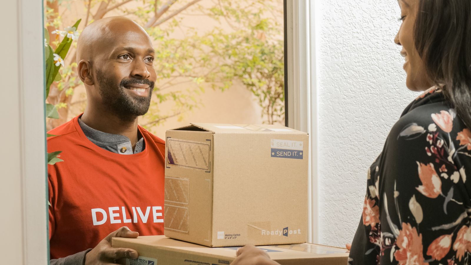 A delivery person handing packages to a smiling customer at the door