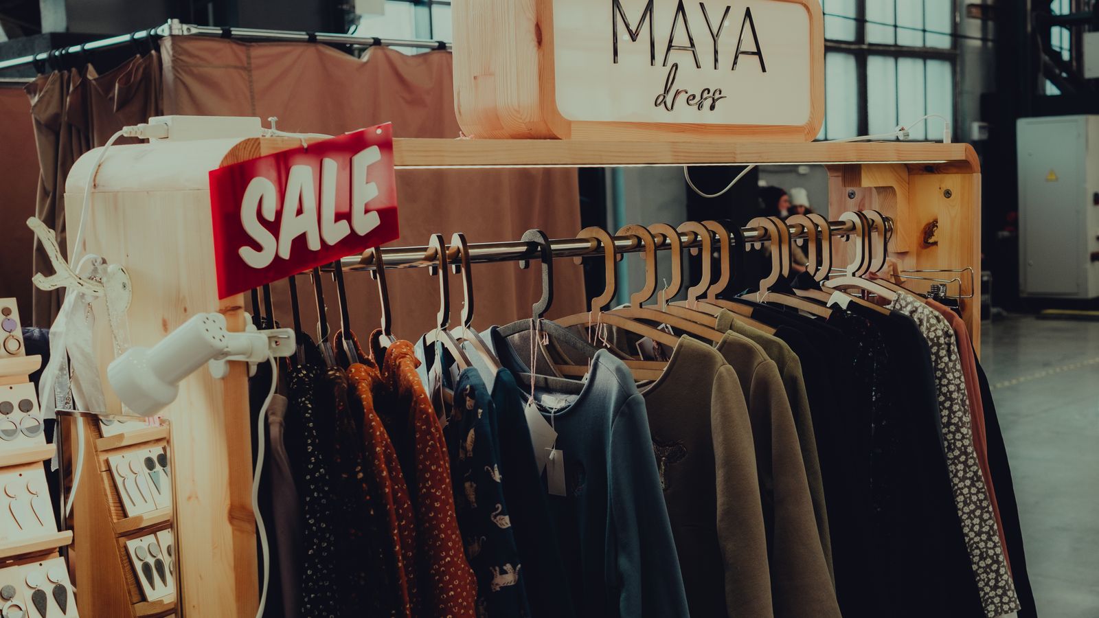 Clothes hanging on a rack with a sale sign in a spacious shop