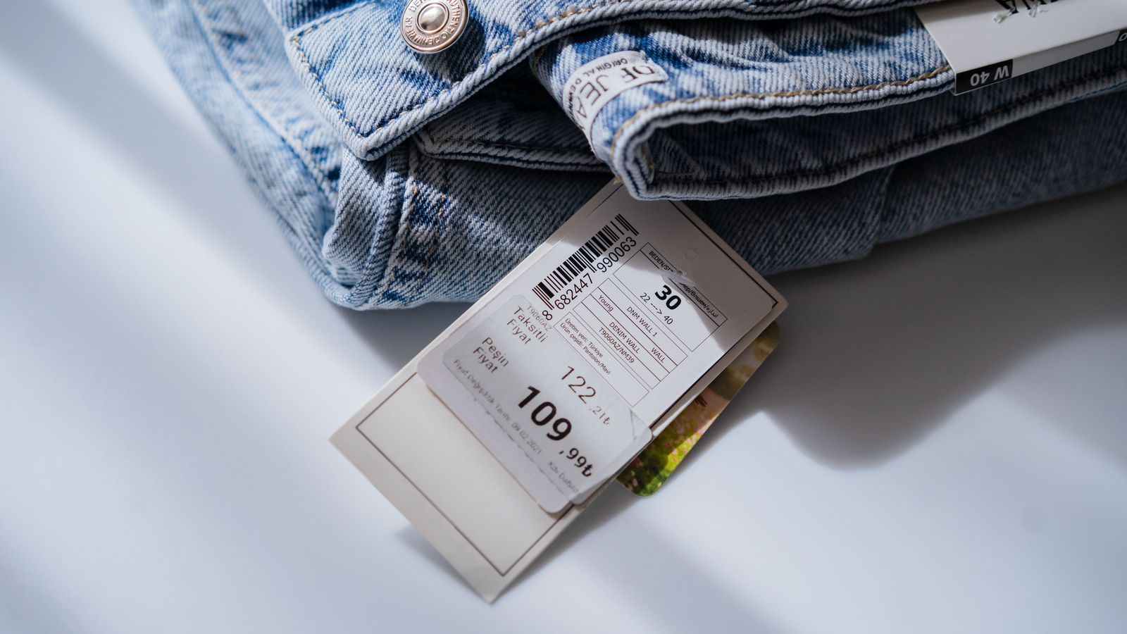 Blue jeans with a retail price and size label on a white table